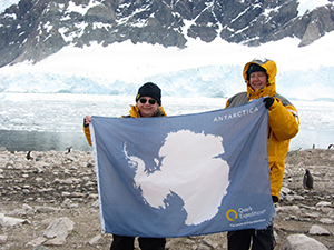 Ruth and her cousin at Neko Harbour with flag showing the continent of Antarctica.