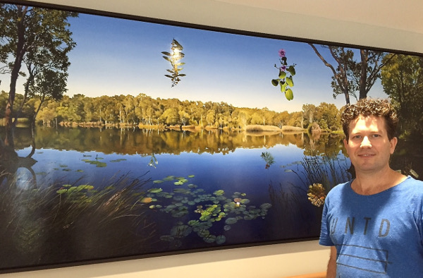 Local artist Hobie Porter with ‘Bush Healing’… his spectacular painting of the melaleuca lake at Tyagarah that graces the entry foyer of the new hospital. The wetland was gouged out by sand mining in the 1960s, and has now healed, making it an apt symbol for a healthcare facility.