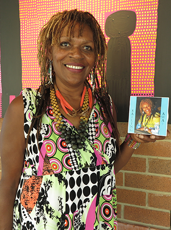 Sheli Nagas with her new CD in front of a painting in Lismore Regional Gallery by Bundjalung artist, Michael Philp.